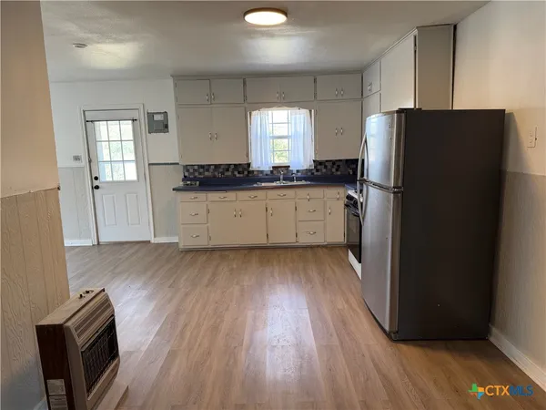 a kitchen with a refrigerator and wooden floor