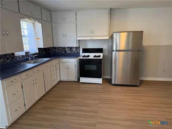 a kitchen with granite countertop a refrigerator and a sink