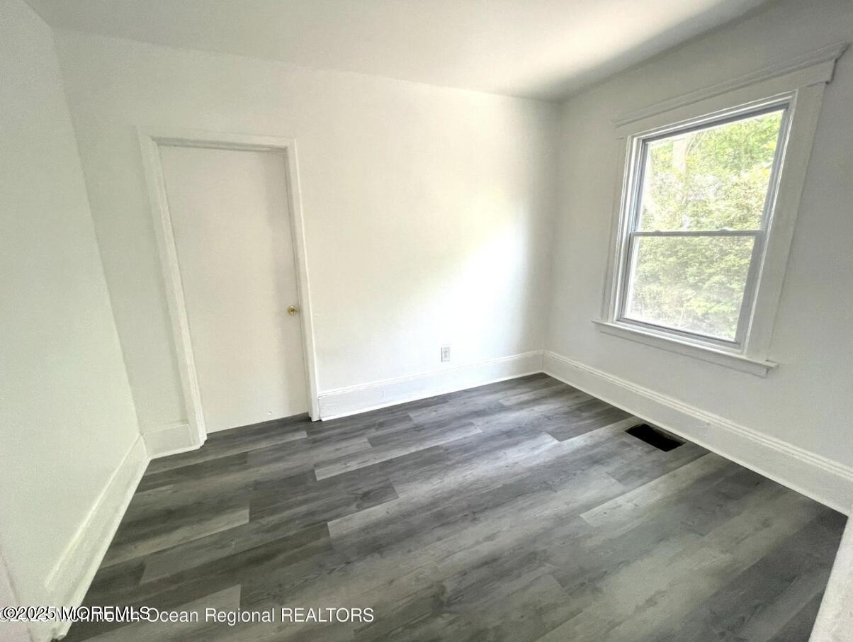 1027 Monroe Avenue, Unit 1 Asbury Park, NJ 07712 - Photo 4 of 10 an empty room with wooden floor and windows