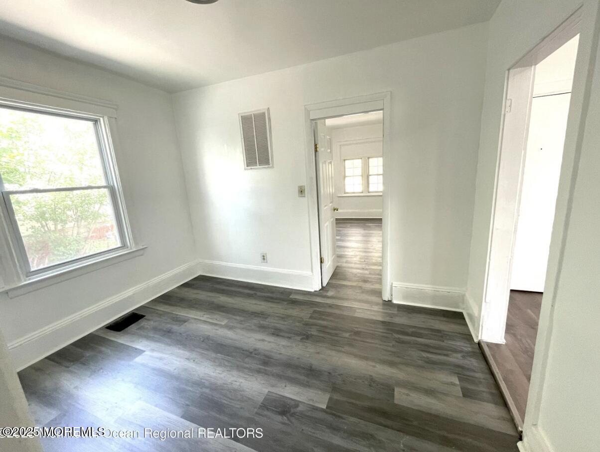 1027 Monroe Avenue, Unit 1 Asbury Park, NJ 07712 - Photo 5 of 10 a view of an empty room with wooden floor and a window