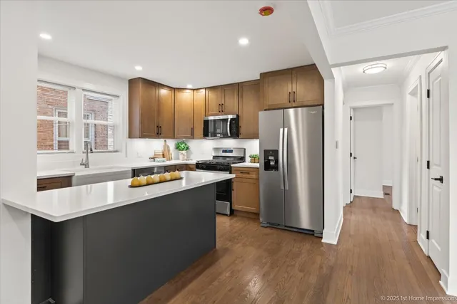 a kitchen with stainless steel appliances granite countertop a refrigerator a sink dishwasher a stove and a refrigerator with wooden floor