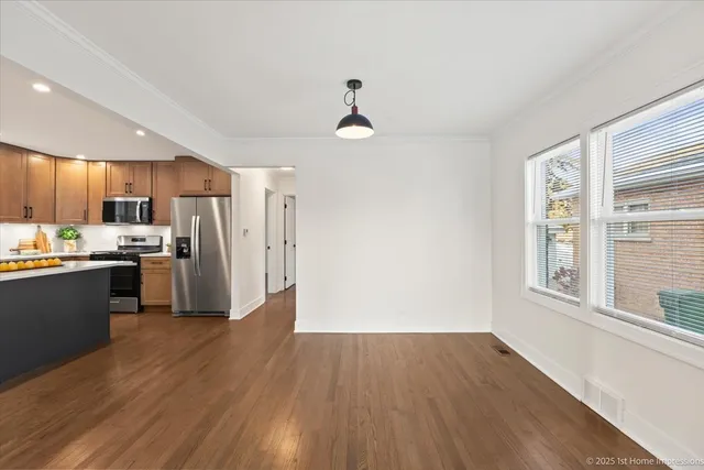 a kitchen with granite countertop a refrigerator and wooden floors