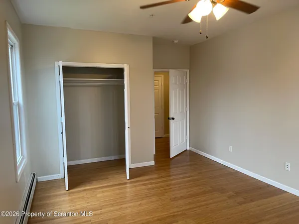 an empty room with wooden floor fan and windows