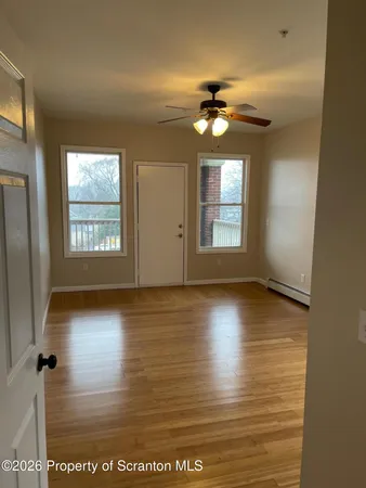 a view of an empty room with window and wooden floor