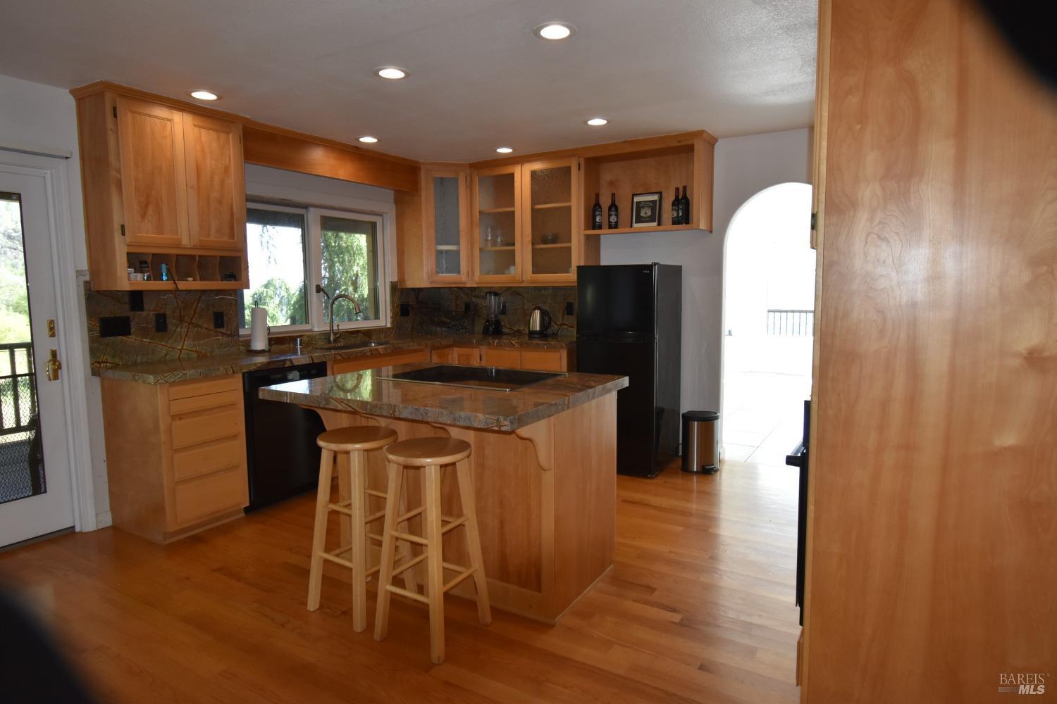 7490 Walnut Lane Lower Lake, CA 95457 - Photo 8 of 44 a kitchen with kitchen island granite countertop wooden floors and a refrigerator