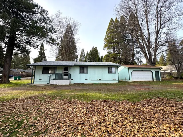 a front view of a house with a garden and trees