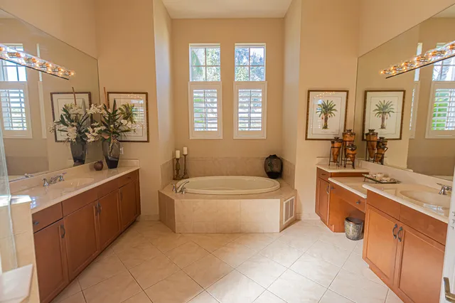 a spacious bathroom with a double vanity sink a large mirror and a bathtub