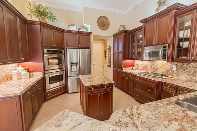 a kitchen with stainless steel appliances kitchen island granite countertop a stove refrigerator and cabinets