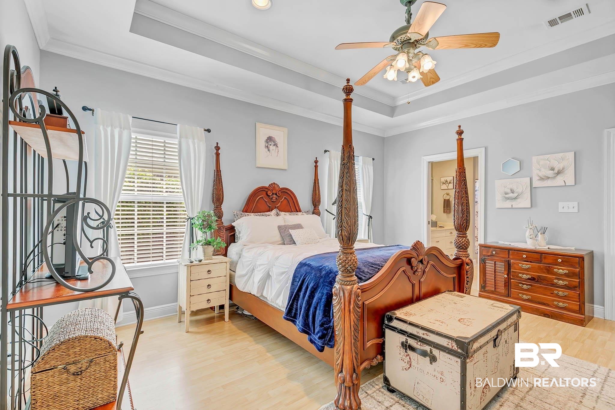 213 Hemingway Loop Foley, AL 36535 - Photo 28 of 69 Bedroom featuring a tray ceiling, light wood finished floors, ornamental molding, a ceiling fan, and ensuite bath