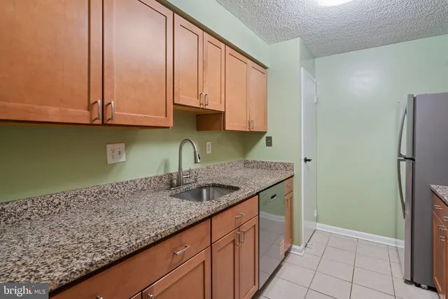 a kitchen with granite countertop a sink and a refrigerator