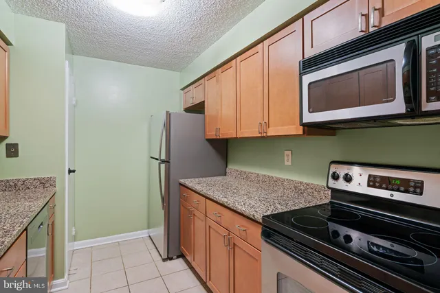 a kitchen with stainless steel appliances granite countertop a stove microwave and refrigerator