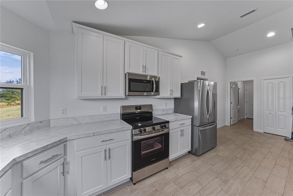 4514 Adrienne Street Sebring, FL 33872 - Photo 28 of 55 a kitchen with refrigerator a microwave a stove and cabinets