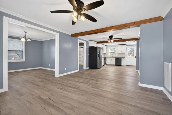 an empty room with wooden floor ceiling fan and windows
