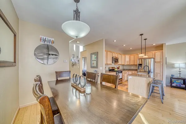 a dining room with wooden floor a chandelier a glass table and chairs