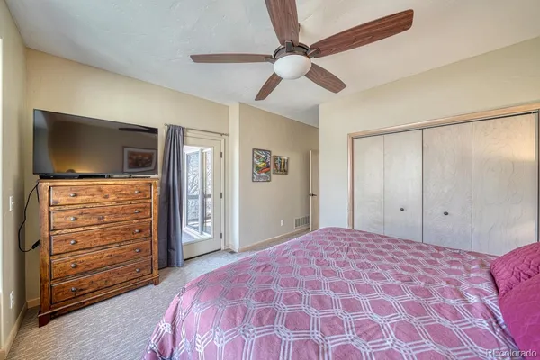 a bedroom with a bed and a flat tv screen on dresser
