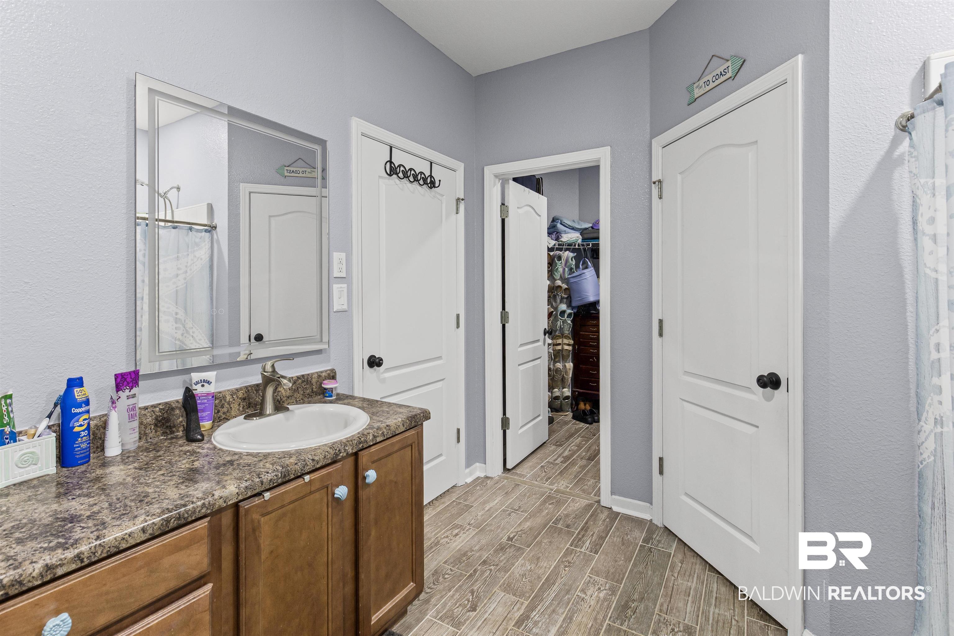 4107 Nottingham Drive Semmes, AL 36575 - Photo 12 of 23 Bathroom with vanity, wood tiled floors, a spacious closet, a textured wall, and a shower
