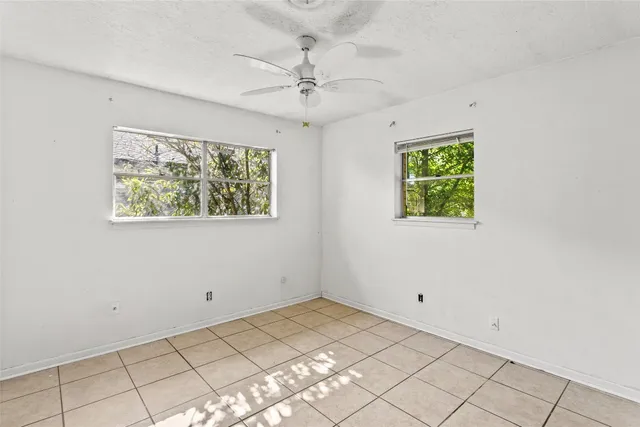 an empty room with windows and fan