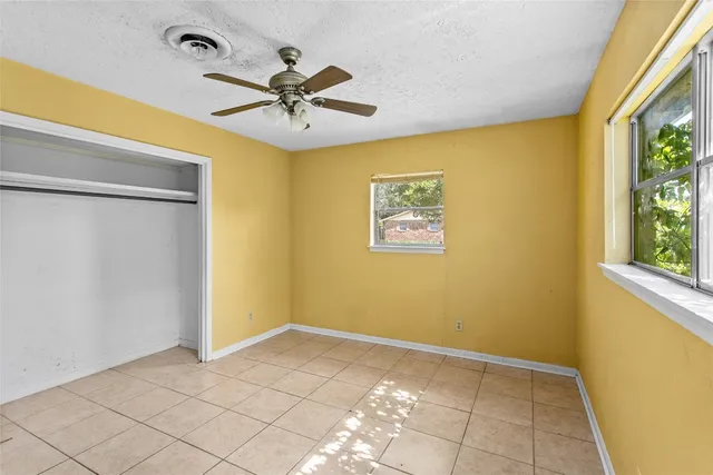 a view of a big room with wooden floor and chandelier fan