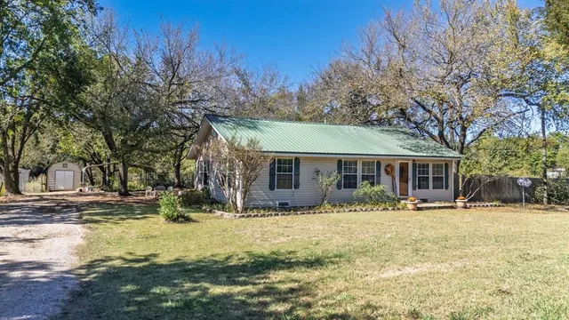 a front view of house with yard and trees in the background
