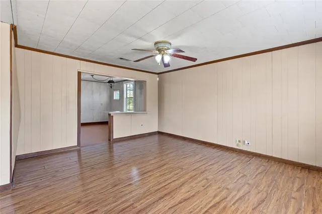 a view of empty room with wooden floor and ceiling fan