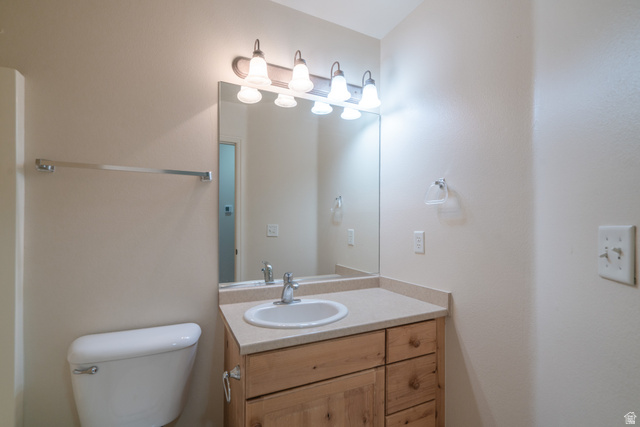 1735 West 540 North, Unit 1805 St. George, UT 84770 - Photo 52 of 64 Bathroom vanity with integrated sink, light-toned countertop, natural wood-finish cabinetry, and a mirrored wall