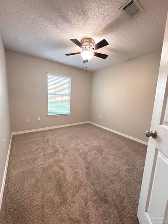 an empty room with windows and fan