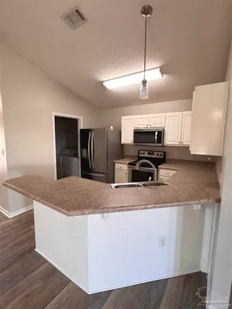 a kitchen with stainless steel appliances granite countertop a sink a stove a refrigerator cabinets and wooden floor