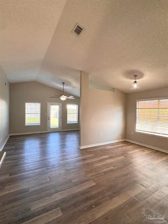 an empty room with wooden floor and windows
