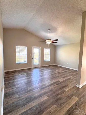 an empty room with wooden floor chandelier and windows