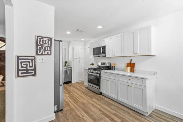 a kitchen with granite countertop cabinets stainless steel appliances and a refrigerator