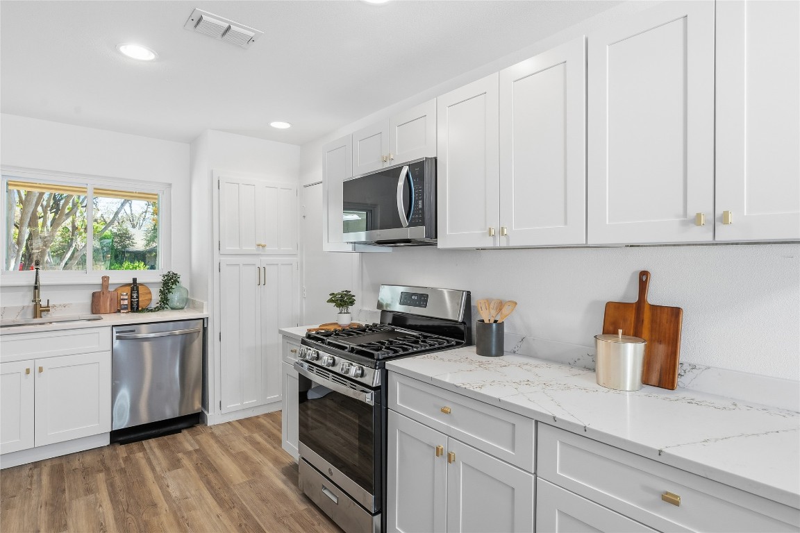 6710 Kings Point West Austin, TX 78723 - Photo 14 of 40 a kitchen with stainless steel appliances granite countertop a stove a sink and a white cabinets