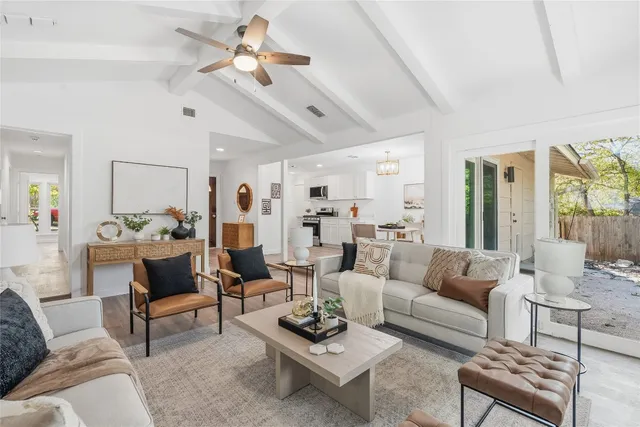 a living room with furniture a rug kitchen view and a chandelier