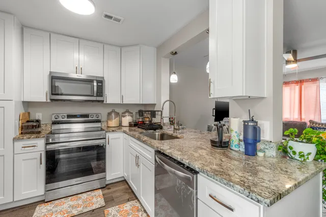 a kitchen with granite countertop a stove top oven microwave and cabinets