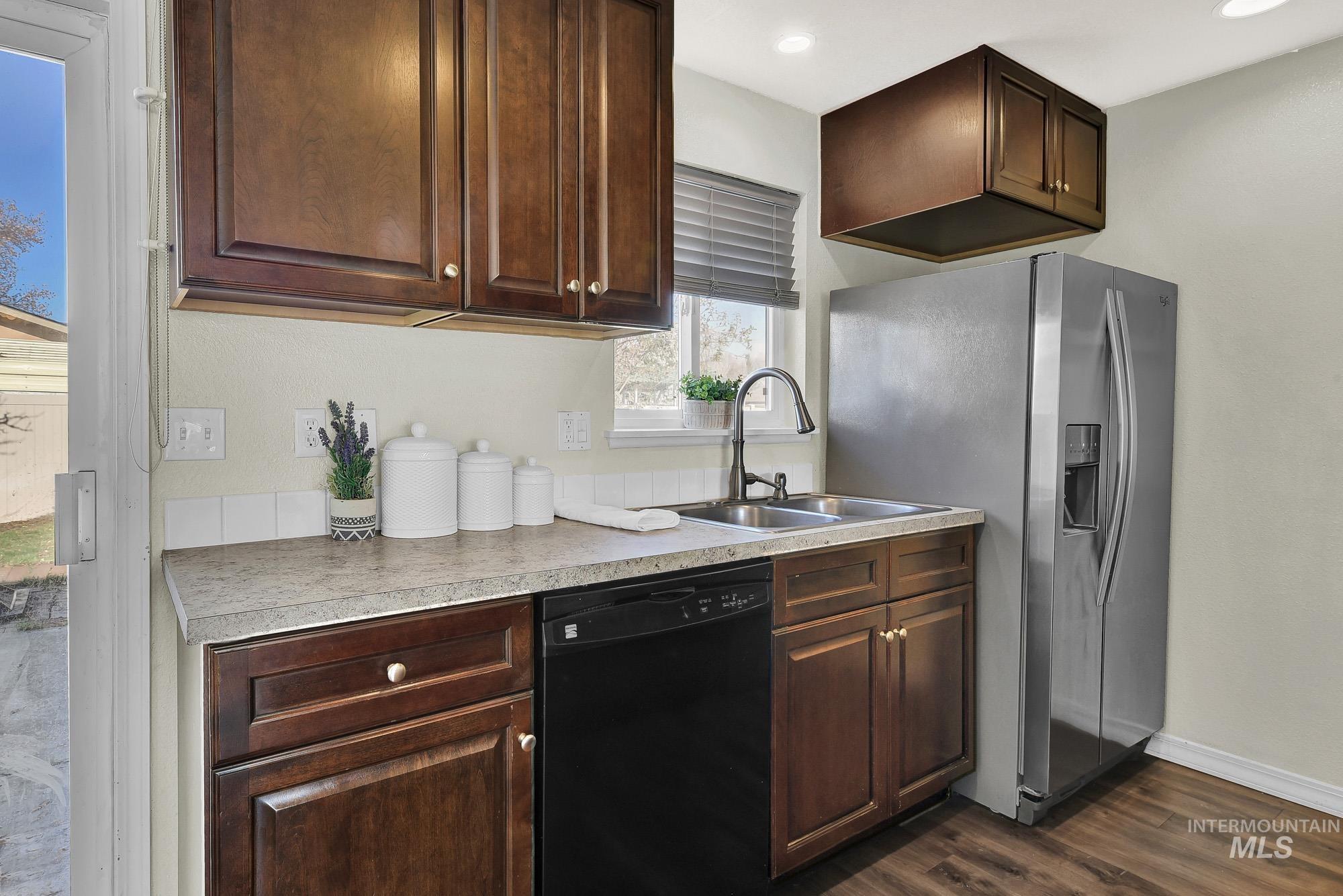 901 East 2nd Street South Middleton, ID 83644 - Photo 11 of 50 Kitchen with black dishwasher, rich brown cabinets, stainless steel refrigerator with ice dispenser, laminate wood-style flooring, and neutral granite style countertops