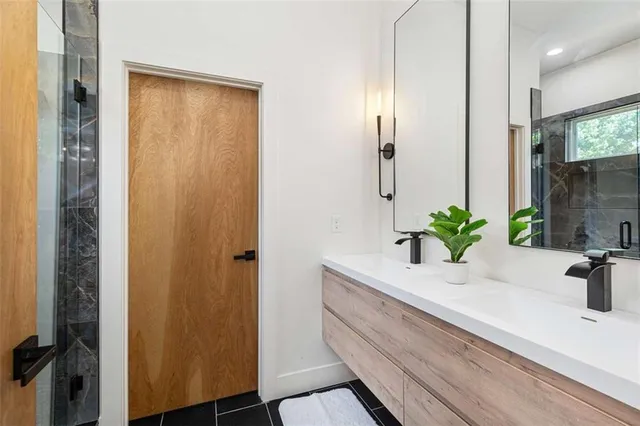 a bathroom with a granite countertop sink a mirror and shower