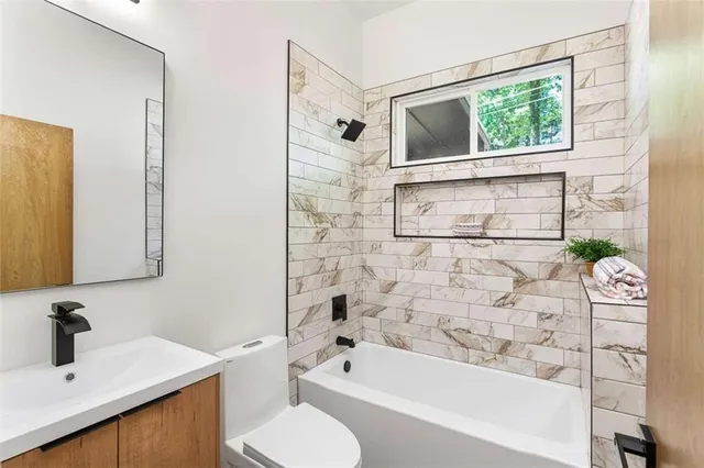 a bathroom with a sink vanity mirror bathtub and toilet