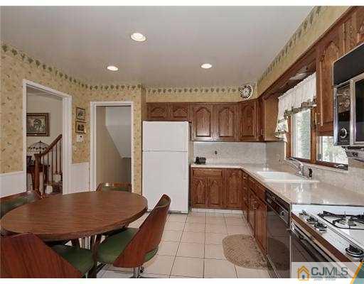 14 Golf Road Edison, NJ 08820 - Photo 6 of 20 a kitchen with stainless steel appliances granite countertop a sink a stove a refrigerator a microwave oven with a dining table and chairs
