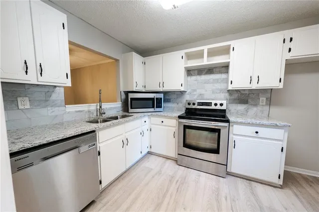 a kitchen with granite countertop a sink stainless steel appliances and cabinets