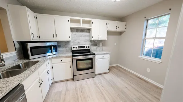 a kitchen with cabinets stainless steel appliances and a window
