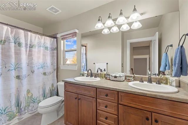 a bathroom with a double vanity sink mirror and toilet