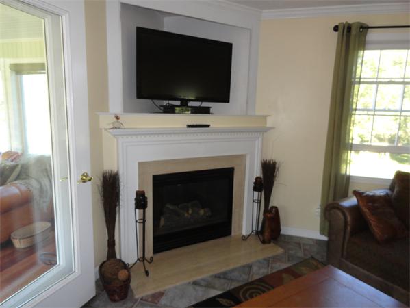 115 Gleasondale Road Stow, MA 01775 - Photo 14 of 14 a living room with a fireplace and a flat screen tv