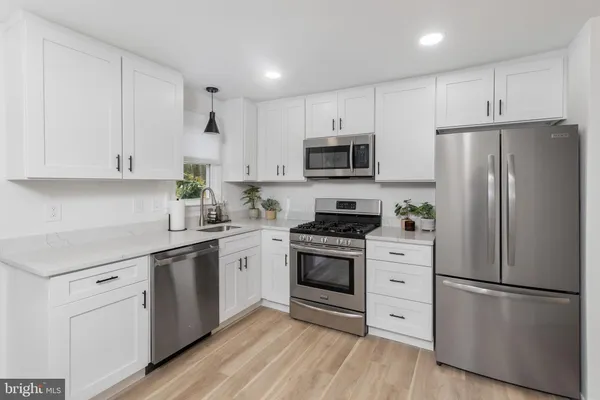a kitchen with cabinets stainless steel appliances and wooden floor