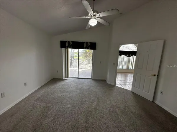 an empty room with windows and ceiling fan