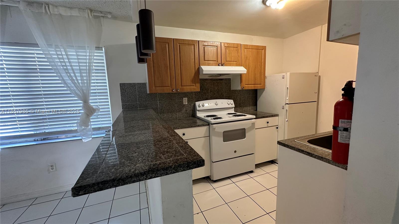 2138 Southwest 6th Street, Unit 102 Miami, FL 33135 - Photo 5 of 11 a kitchen with white cabinets and white appliances