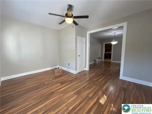 a view of a room with wooden floor and a ceiling fan