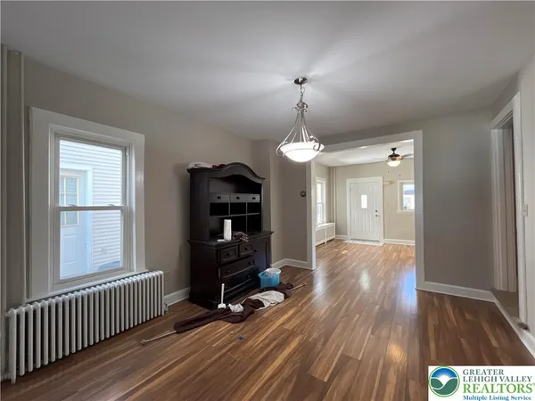 a view of empty room with wooden floor and fan