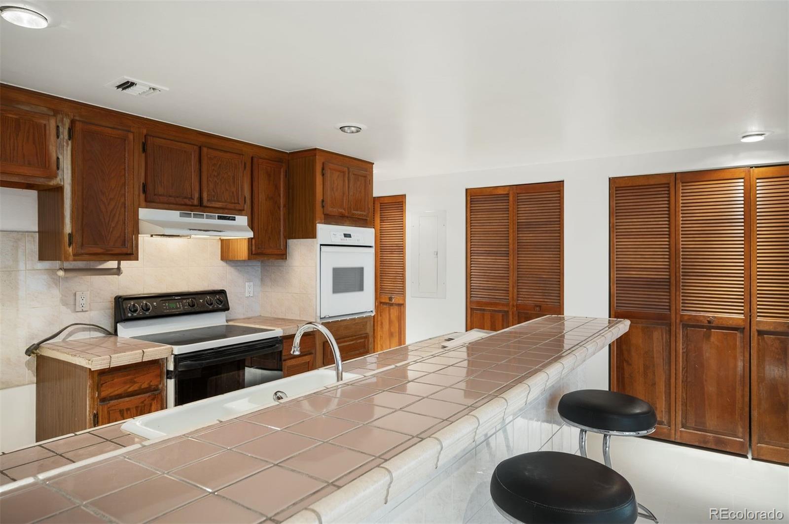 1777 Larimer Street, Unit 1010 Denver, CO 80202 - Photo 15 of 48 a kitchen with granite countertop a stove and a wooden cabinets