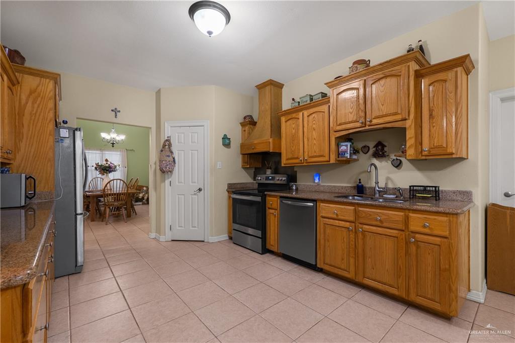 605 South Whalen Road Donna, TX 78537 - Photo 8 of 21 Kitchen featuring wood cabinetry, stainless steel appliances, a built-in wood range hood, and tile flooring