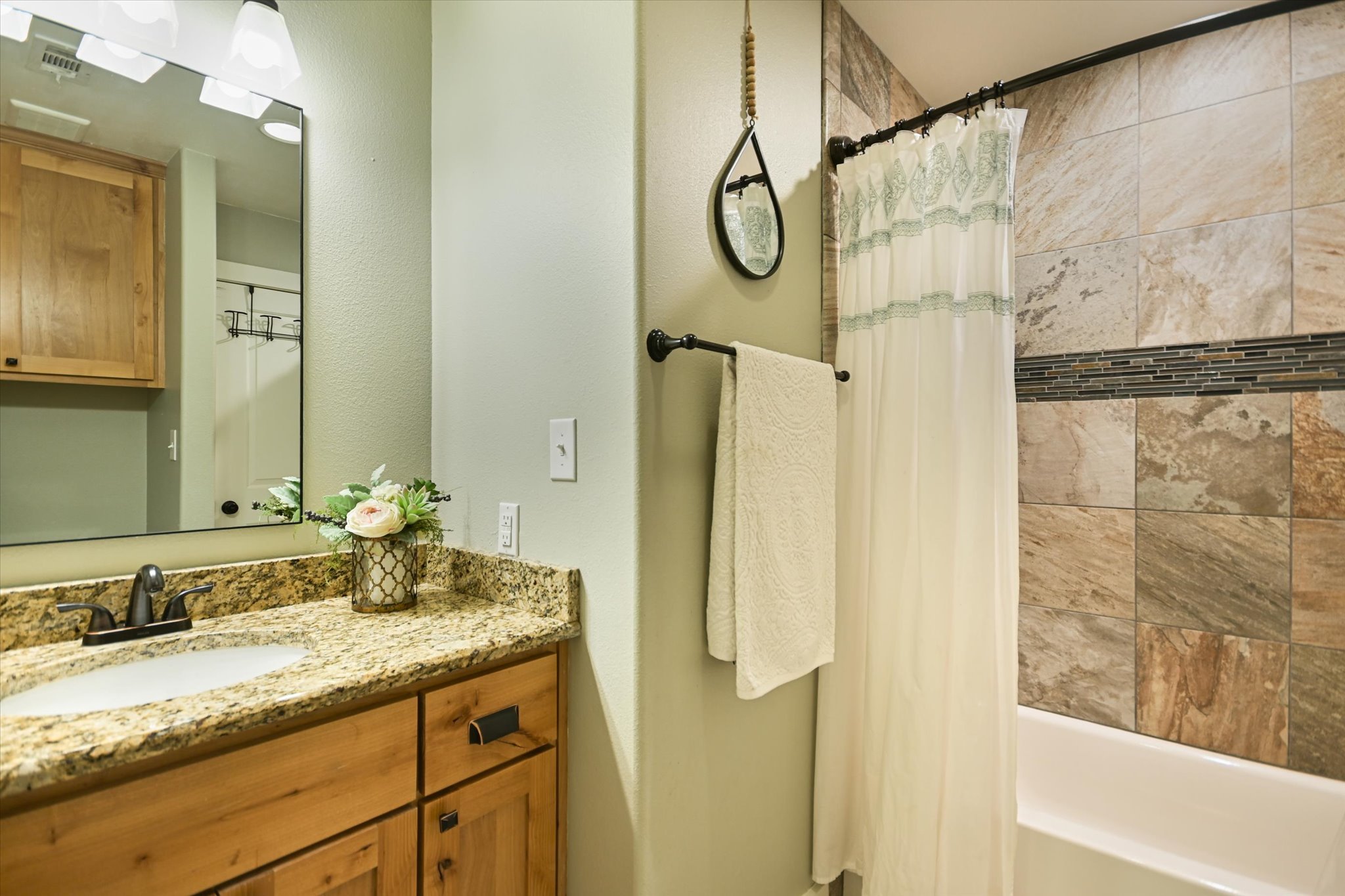 2411 Spoke Hollow Road Wimberley, TX 78676 - Photo 17 of 37 A well-appointed bathroom features a sleek vanity with a spacious granite counter and tiled shower.