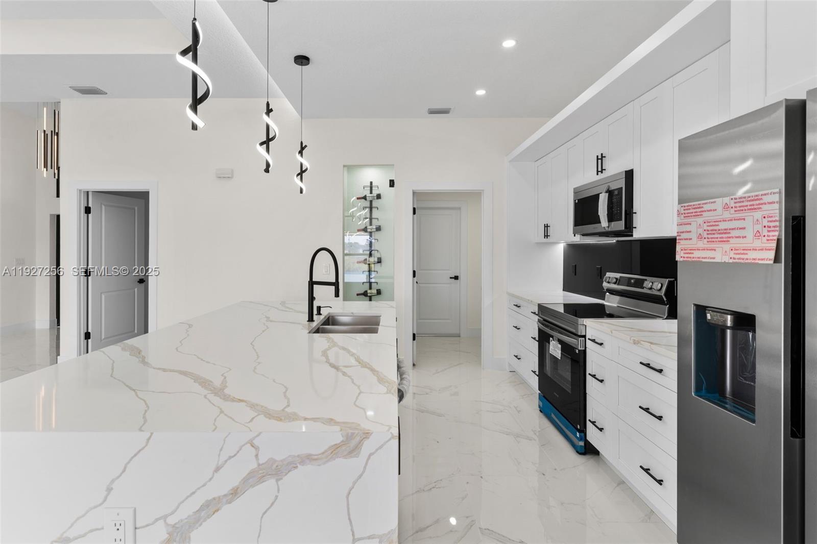 3419 16th Street Southwest Lehigh Acres, FL 33976 - Photo 7 of 46 a large white kitchen with kitchen island a sink stainless steel appliances and cabinets